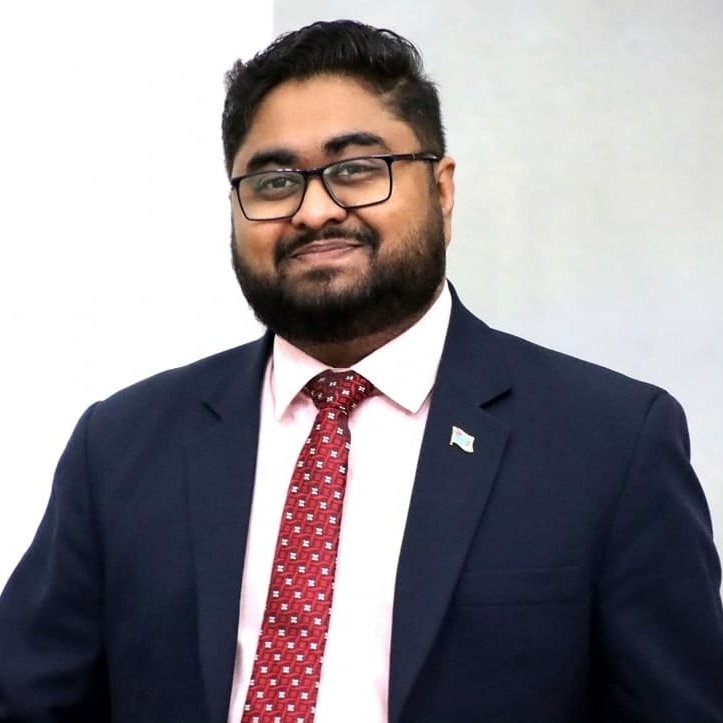 Hon. Ketan Lal in a navy suit and red tie
